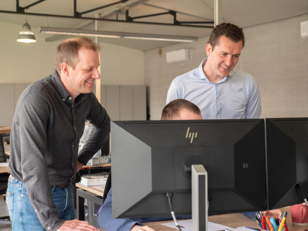 Drie Incomec-medewerkers overleggen samen aan een computer op kantoor.