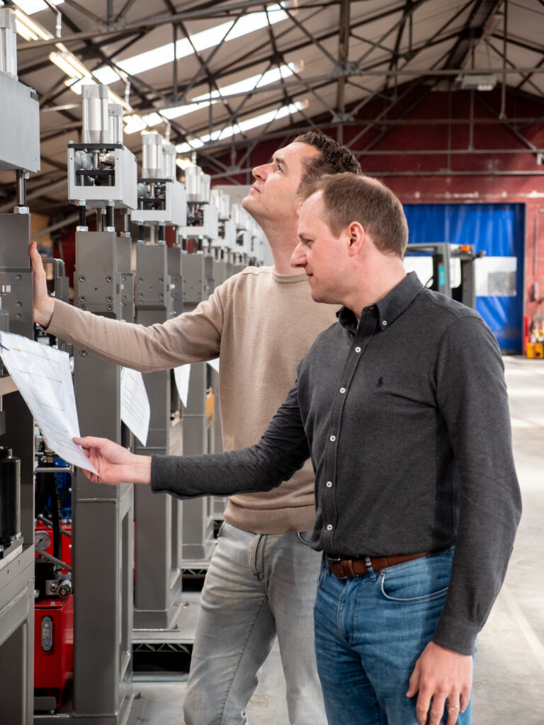 Twee Incomec-medewerkers controleren samen industriële machines voor de productie van gepofte snacks.